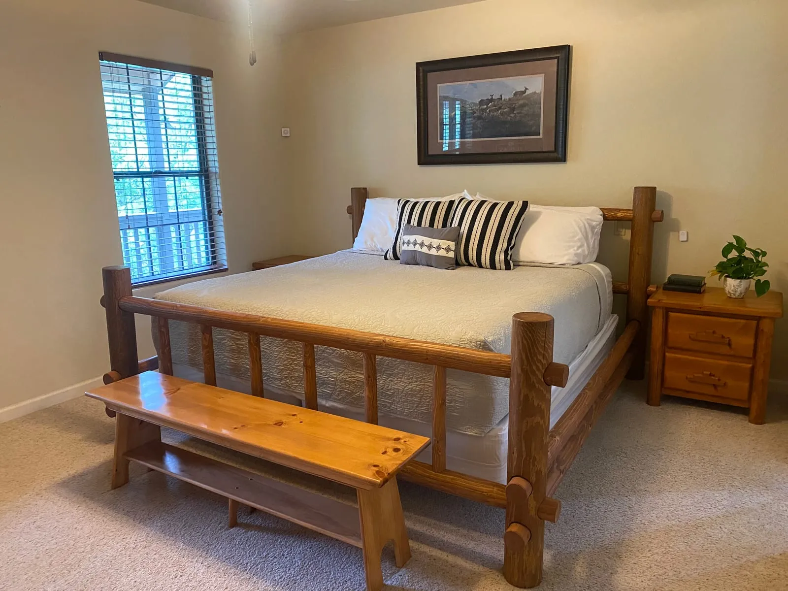 Bedroom with a cozy bed, a bench at the foot, and framed art