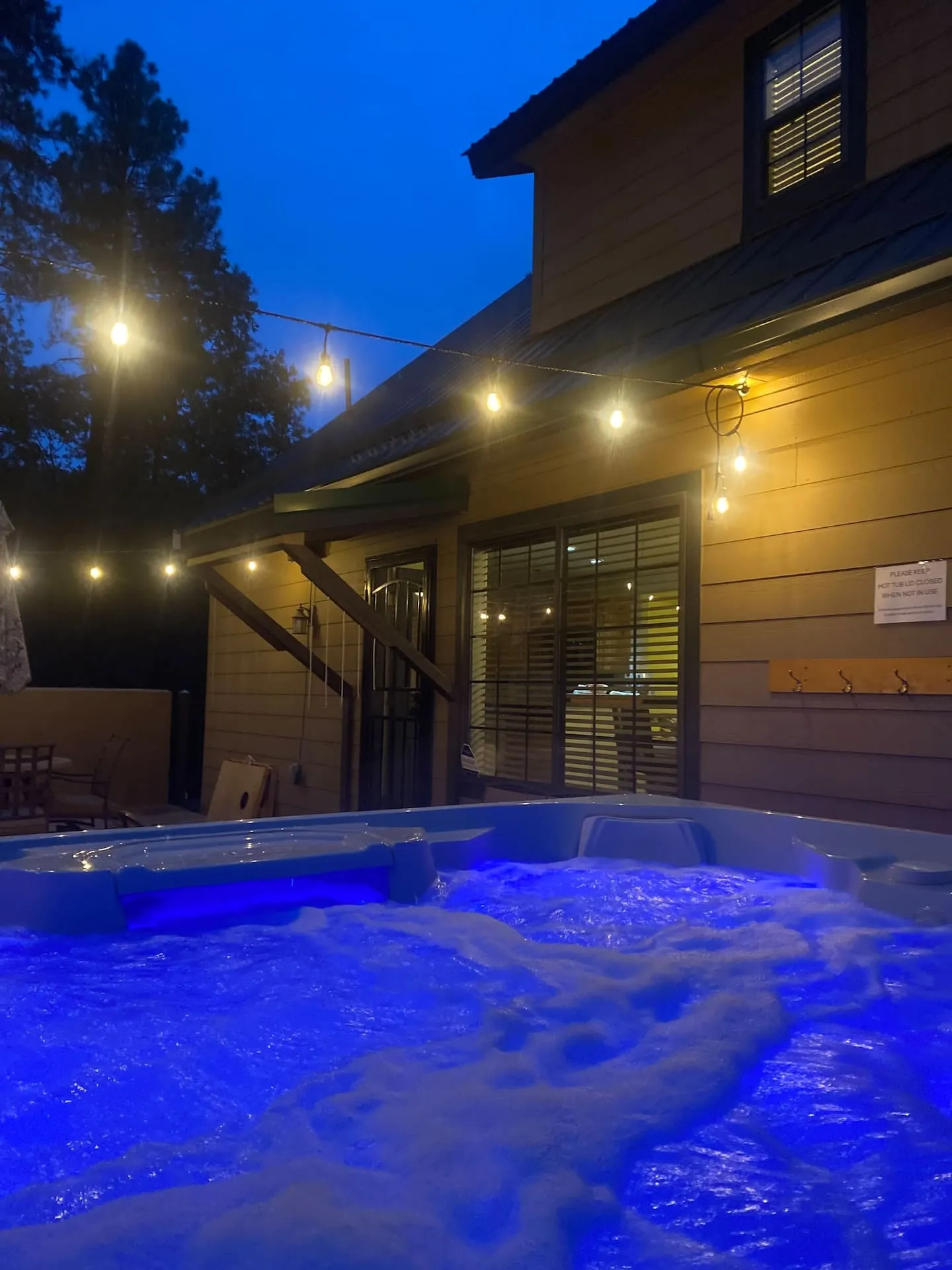 Two glasses by a cabin hot tub at dusk in the pines