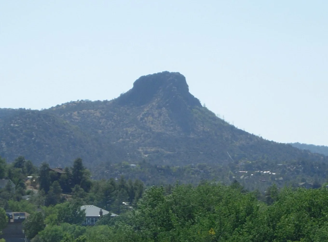 The blunt basalt summit of Thumb Butte rising above pines and rooftops on the western edge of Prescott